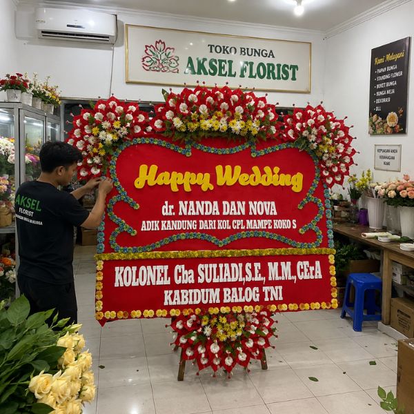 Perangkai sedang melakukan finishing papan bunga pernikahan Medan di workshop Aksel Florist.